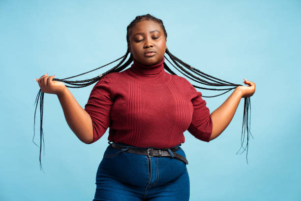 cheerful african american woman with stylish braids, wearing casual clothes, red sweater and denim - braids african descent women pensive imagens e fotografias de stock