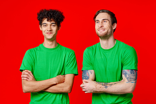 two friends green t-shirts fun red background communication. High quality photo