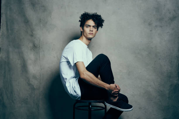 cute guy with curly hair sitting on a chair studio. High quality photo