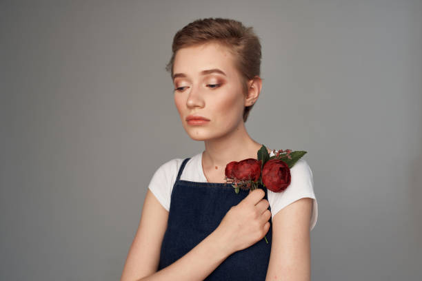 Portrait of beautiful young woman with brown eyes and hair in bun and white fascinator, wearing white top tied on neck with nude shoulders and back, looking at camera, studio shot
