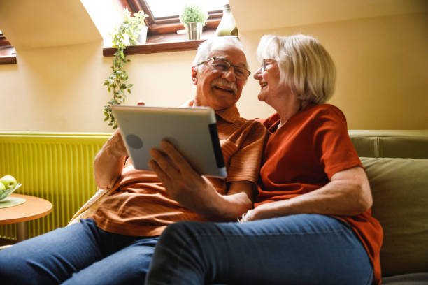 istock Senior couple lounging on sofa and using digital tablet 2054097028