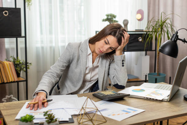 istock Depressed desperate businesswoman feeling worried about financial problem doing paperwork at office 2054104710