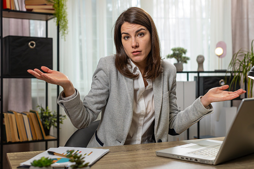 I don't know what to say. Confused businesswoman working on laptop at home office table. Freelancer feeling embarrassed about ambiguous question having doubts, no answer idea being clueless uncertain