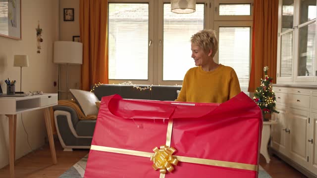 Happy woman opening a massive Christmas gift