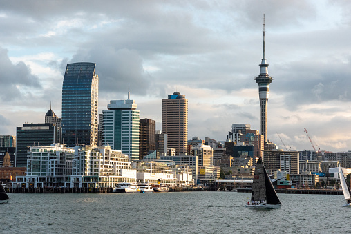 Auckland, New Zealand - January 25, 2023 - Famous skyline of Auckland Central Business District during sunset, people anjoying the warm summer evening on their sailboats, New Zealand