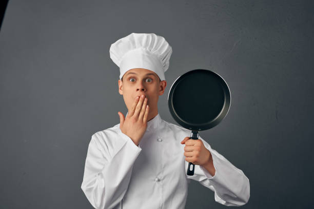 istock Cheerful chef in restaurant uniform with frying pan in kitchen hands 2054215305