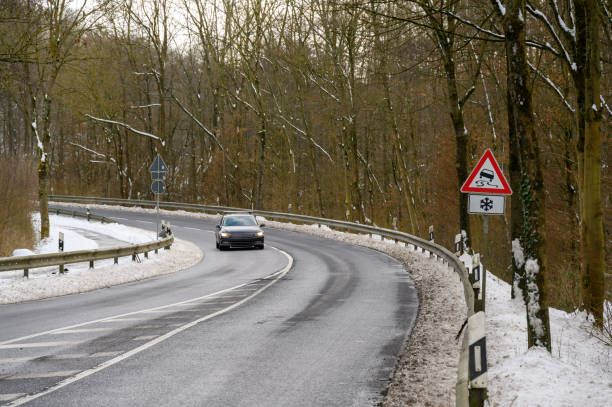 istock Winding road in winter with snow and a car approaching 2054228497