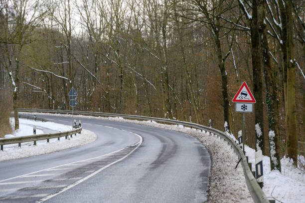 istock Slippery road sign on a winding road in winter 2054228703