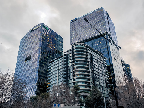 Melbourne, Australia - Aug 30, 2022: Modern high-rise office buildings (KMPG and Transurban). Upward perspective view from street level (Wurundjeri Way, Docklands). Overcast sky.