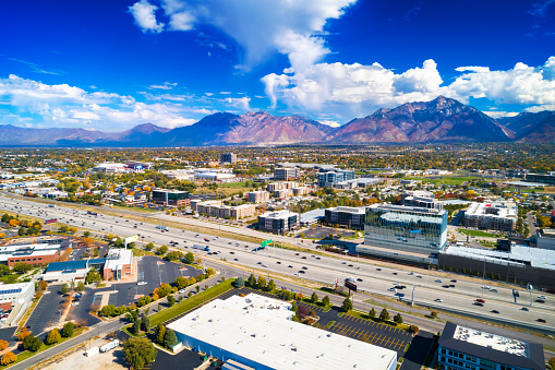 Aerial of Sandy, Utah during Autumn with I-15 in the foreground, and the Wasatch Range and a blue sky with cumulus clouds in the background.  Sandy is part of the Salt Lake City metropolitan area.