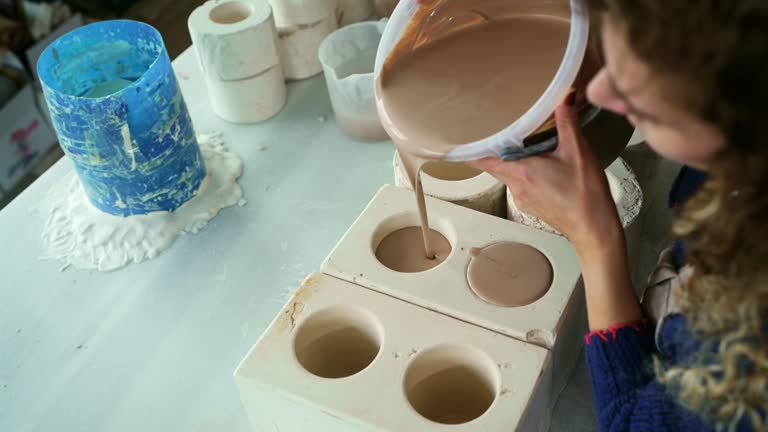 Woman pouring clay into the plaster molds.