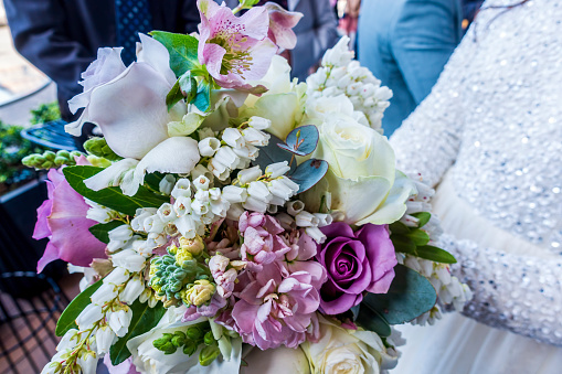 Close-up of colorful floral wedding bouquet consisting of numerous flower types, bundled up into a small bunch for handheld purposes.