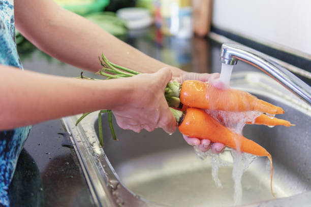 istock Woman hands washing fresh orange carrots in a kitchen 2054542375