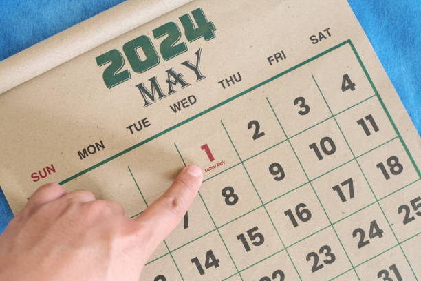istock Hand pointing on May 1 2024 date on calendar flat lay in blue background. Labor day or International workers day celebration reminder. 2054556992
