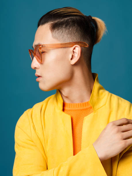 istock Asian man with glasses and a jacket on a blue background side view 2054558719