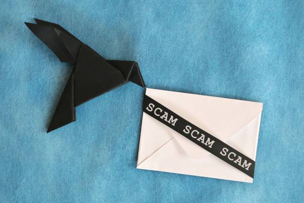 istock Black raven paper origami carrying white letter envelope with word scam. Scam message concept. 2054562207