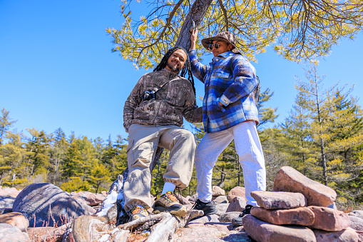 Romantic couple of Latin American man with dreadlocks and beard and Latino woman in hat exploring Boulder Field - Ice Age geological formation in Hickory Run State Park, Poconos region, Pennsylvania