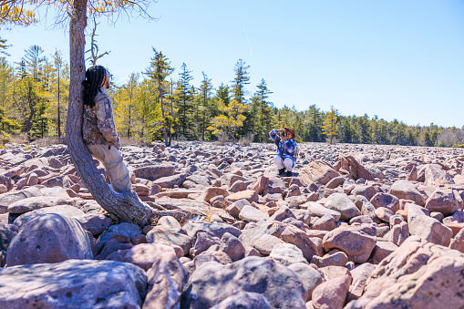 Family photo shooting in extreme terrain. Exploring Boulder Field - Ice Age geological formation in Hickory Run State Park, Poconos region, Pennsylvania
