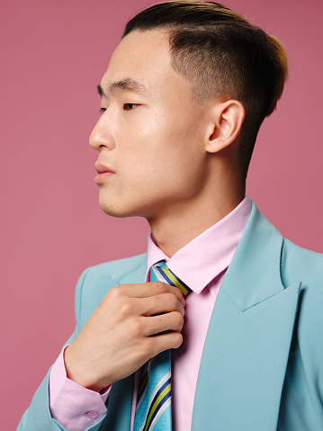 Man of Asian appearance in suit cropped view pink background. High quality photo