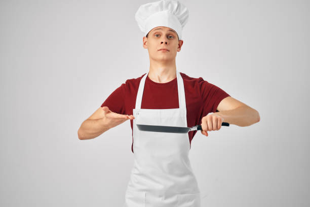 a man in a white apron a frying pan in his hands preparing food for professionals light background