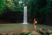 Woman standing near the refreshing waterfall on Bali