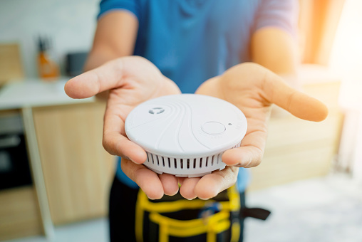 Technician installing fire safety detector in a modern apartment.