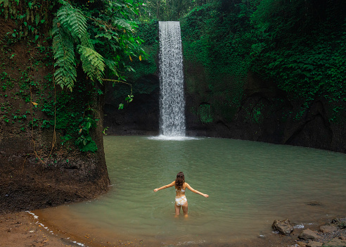 Woman in swimwear swimming in the waterfall on Bali