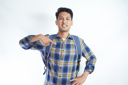 Excited young Asian student man 20s wearing casual clothes with backpack pointing his finger at himself isolated on white background. High school university college concept