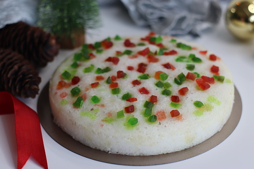 Vattayappam with tutti fruity, a Kerala sweet dish. Vattayappam is a steamed rice cake with coconut and yeast. Tutti fruity are candied fruits. Shot on white background with Christmas decorations