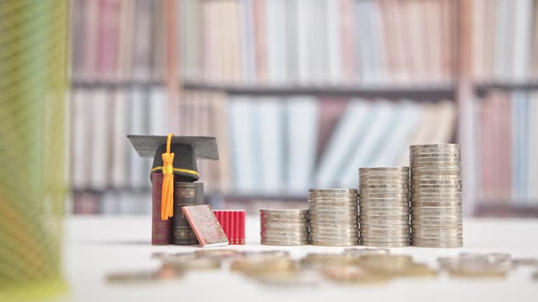Student loans : Financial aid helping students afford higher education. Borrowed funds for college or university expenses. Black graduation cap, books and increasing height coin stacks on a table.