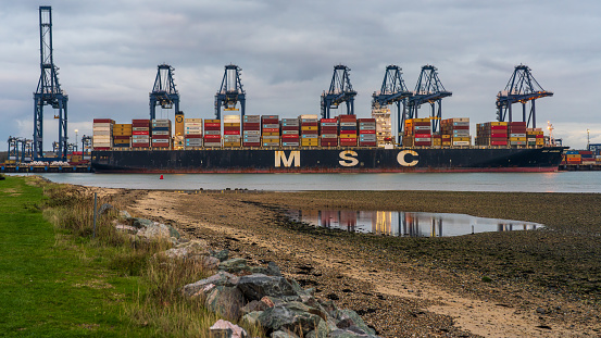 Shotley Gate, Suffolk, England, UK - November 22, 2022: View across the River Orwell to a cargo ship at Felixstowe Harbour