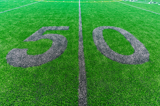 Synthetic turf football 50 yard line and block style numbers in gray.  Practice football turf markings are less obvious and installed in the outfield of a baseball field.