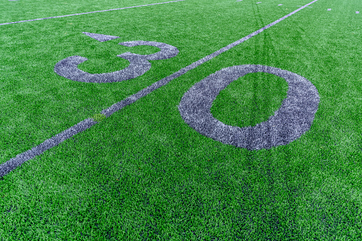 Synthetic turf football 30 yard line and block style numbers in gray.  Practice football turf markings are less obvious and installed in the outfield of a baseball field.