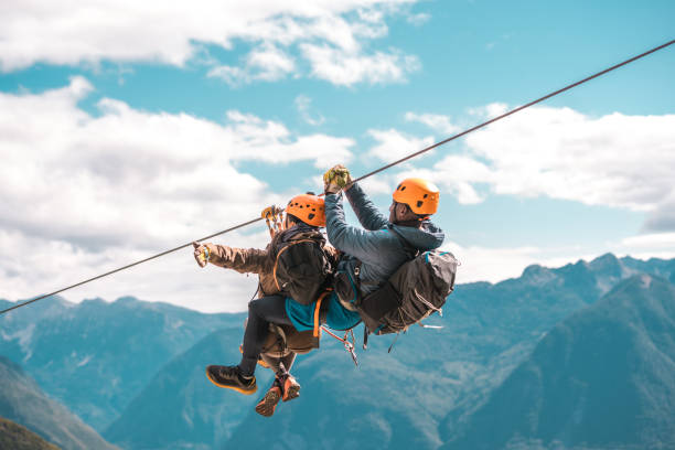 Young couple starting an elevated zip-line experience on a mountain expedition conquering heights and experiencing the rush of wind in an adrenaline-fueled outdoor escapade.