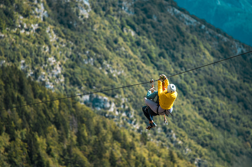 Young couple starting an elevated zip-line experience on a mountain expedition conquering heights and experiencing the rush of wind in an adrenaline-fueled outdoor escapade.