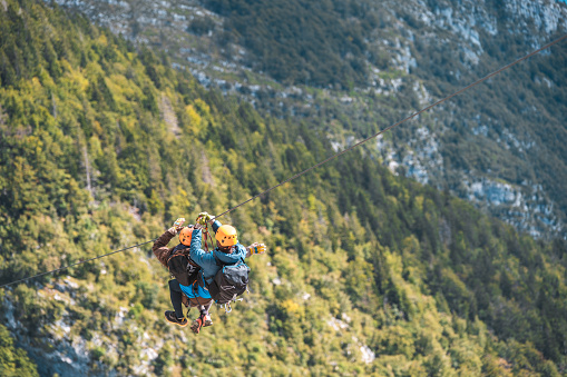 Young couple starting an elevated zip-line experience on a mountain expedition conquering heights and experiencing the rush of wind in an adrenaline-fueled outdoor escapade.