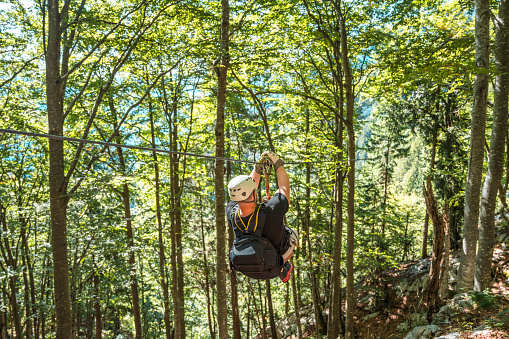Young adventurer glides through the lush forest canopy where ziplines thread between ancient trees embracing a thrilling journey immersed in nature's beauty.