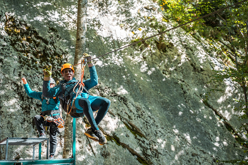 Happy adventurer discovering the serenity of ziplining through towering trees and verdant foliage immersing in the beauty of nature.