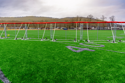 Synthetic turf football 40 yard line and block style numbers in gray with a portable baseball outfield fence.