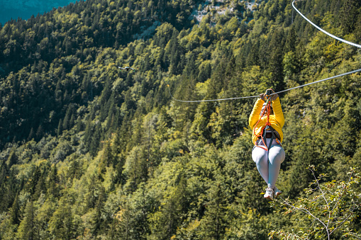 Happy young black male gliding through the mountainous terrain on an adrenaline-charged zip-line journey where the fusion of speed height and nature creates an unforgettable outdoor spectacle.