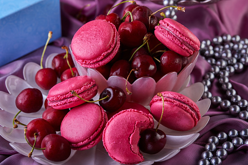 A creative arts event showcasing a product display of a bowl of cherries next to a bowl of pink macarons, highlighting the natural foods and magenta color palette