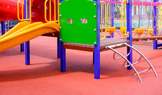 Group of colorful modern playground equipment on rubber floor in outdoors playground area at kindergarten