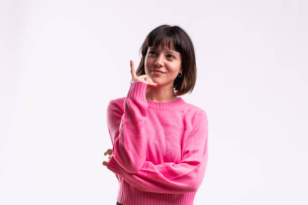 Studio portrait with white background of a young woman pointing up to the copy space
