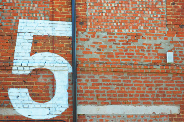 istock Painted white figure, number five on a red brick wall. 2054922265