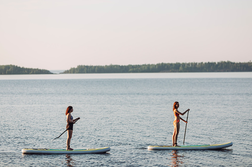 Two women paddleboarding at the lake at sunset