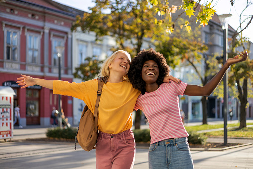 Photo of Two Emotional Happy Multiracial Woman Hugging Each Other on City Street