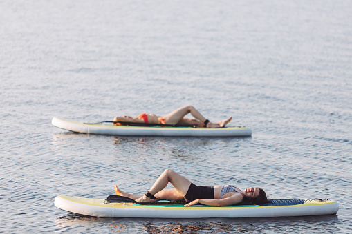 Two mid adult women relaxing at paddleboard