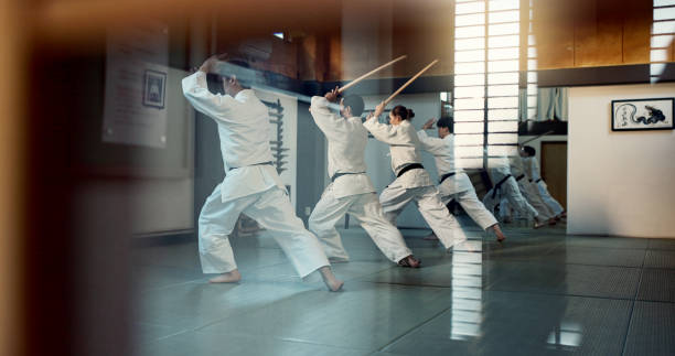 istock Aikido, dojo class and people training for self defense, combat and Japanese group practice sword technique. Black belt students, transparent window and learning martial arts for safety protection 2054929593