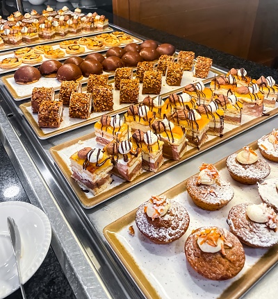 Assortment of small cakes and sweets at a hotel buffet. Squared.