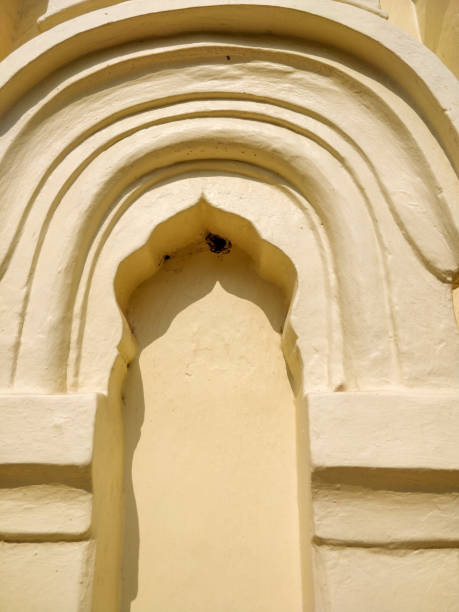Close-up of a yellow arched niche in a white wall